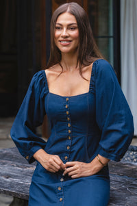 Woman wearing a blue dress with puffed sleeves outdoors