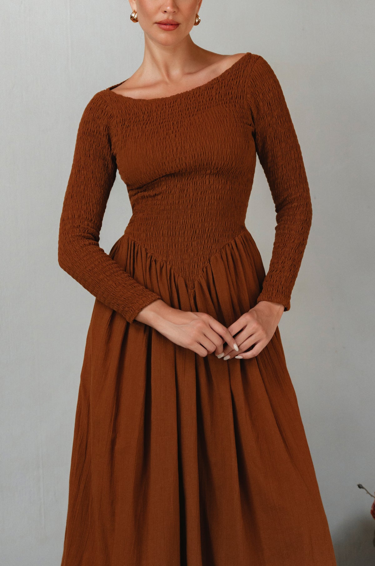 Brown smocked dress worn by a model against a plain background