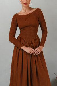 Brown smocked dress worn by a model against a plain background