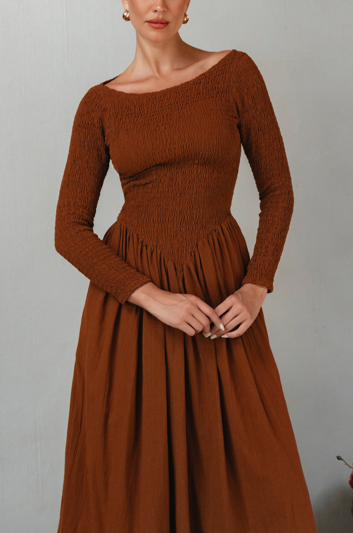 Brown smocked dress worn by a model against a plain background