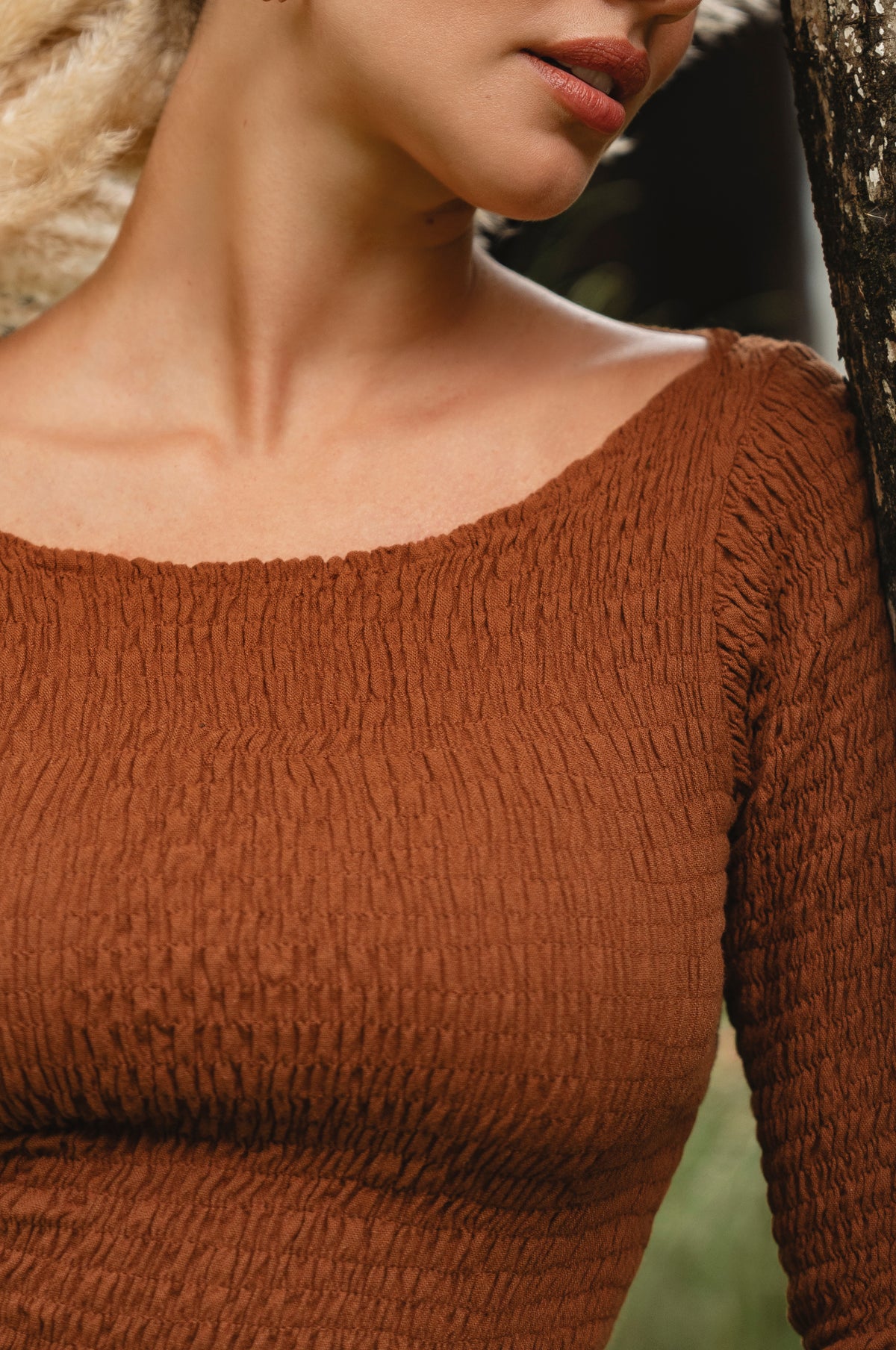 Close-up of a person wearing a brown textured dress with a blurred background