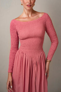 Pink smocked dress worn by a model against a neutral background