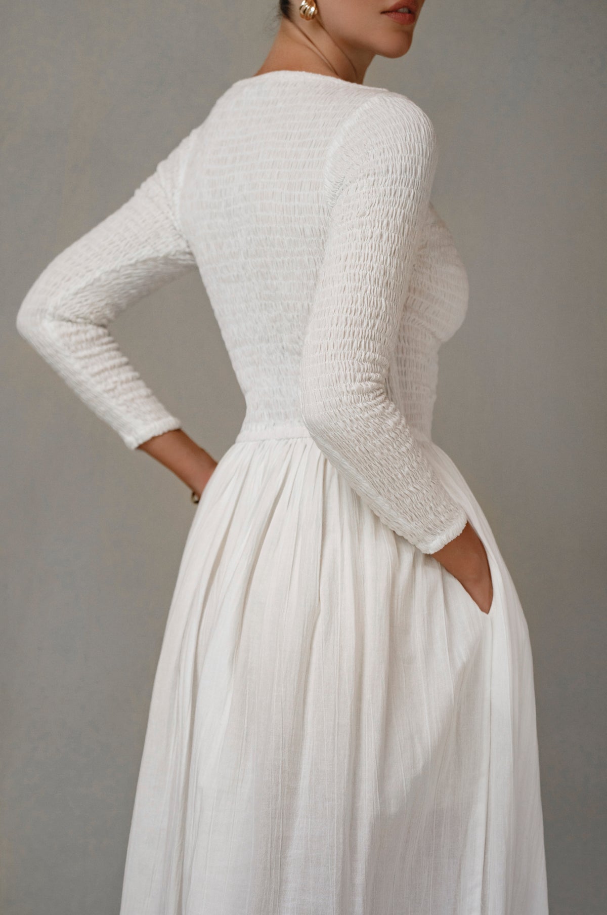 white smocked long sleeve midi dress on a plain background