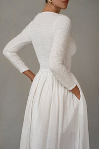 white smocked long sleeve midi dress on a plain background