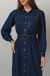 Woman wearing a blue denim dress with a belt against a neutral background