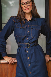 Woman wearing a blue denim dress with a belt, standing indoors - cottage core style