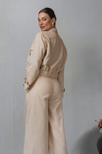 Woman wearing a beige outfit against a plain background