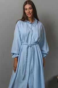 Woman wearing a light blue dress against a gray background