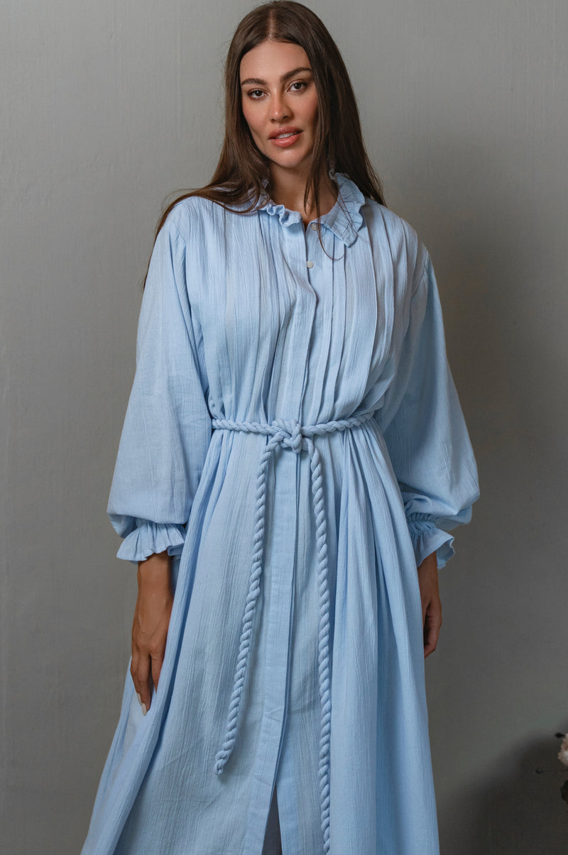 Woman wearing a light blue dress against a gray background